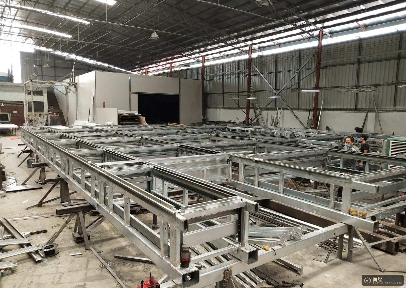 Rows of galvanised steel sub-frames for facade panels laid out on trestles in a metalwork workshop