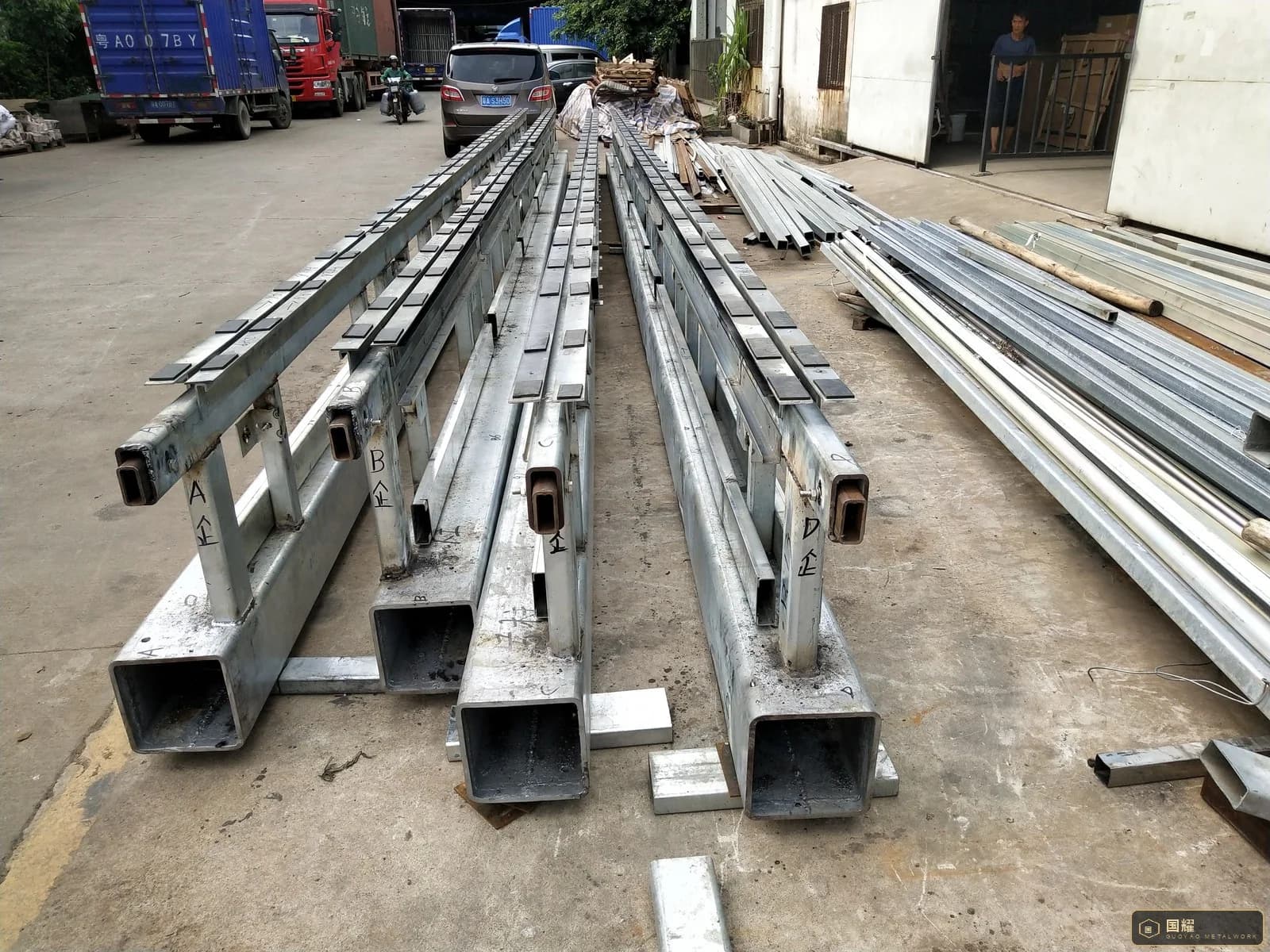Long metal profiles and frames stacked on timber bearers outdoors ready for packing