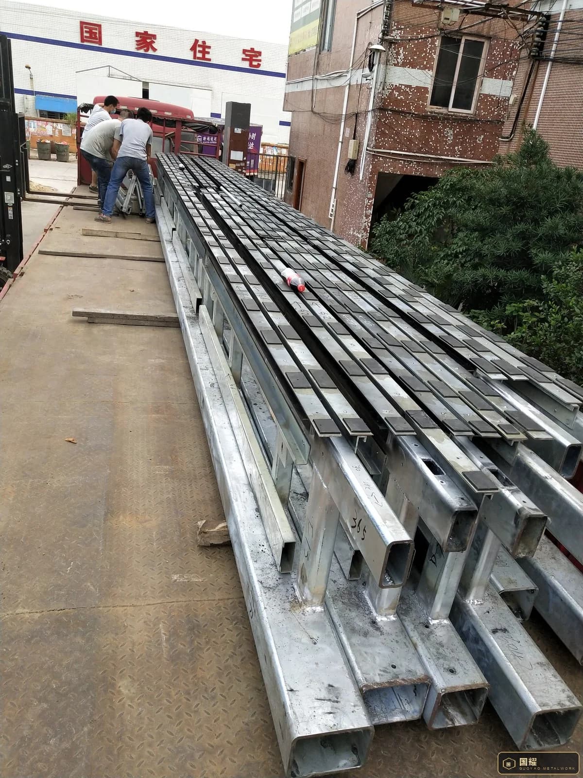 Loaded flat rack seen from above with straps over timber packers protecting the metal panels